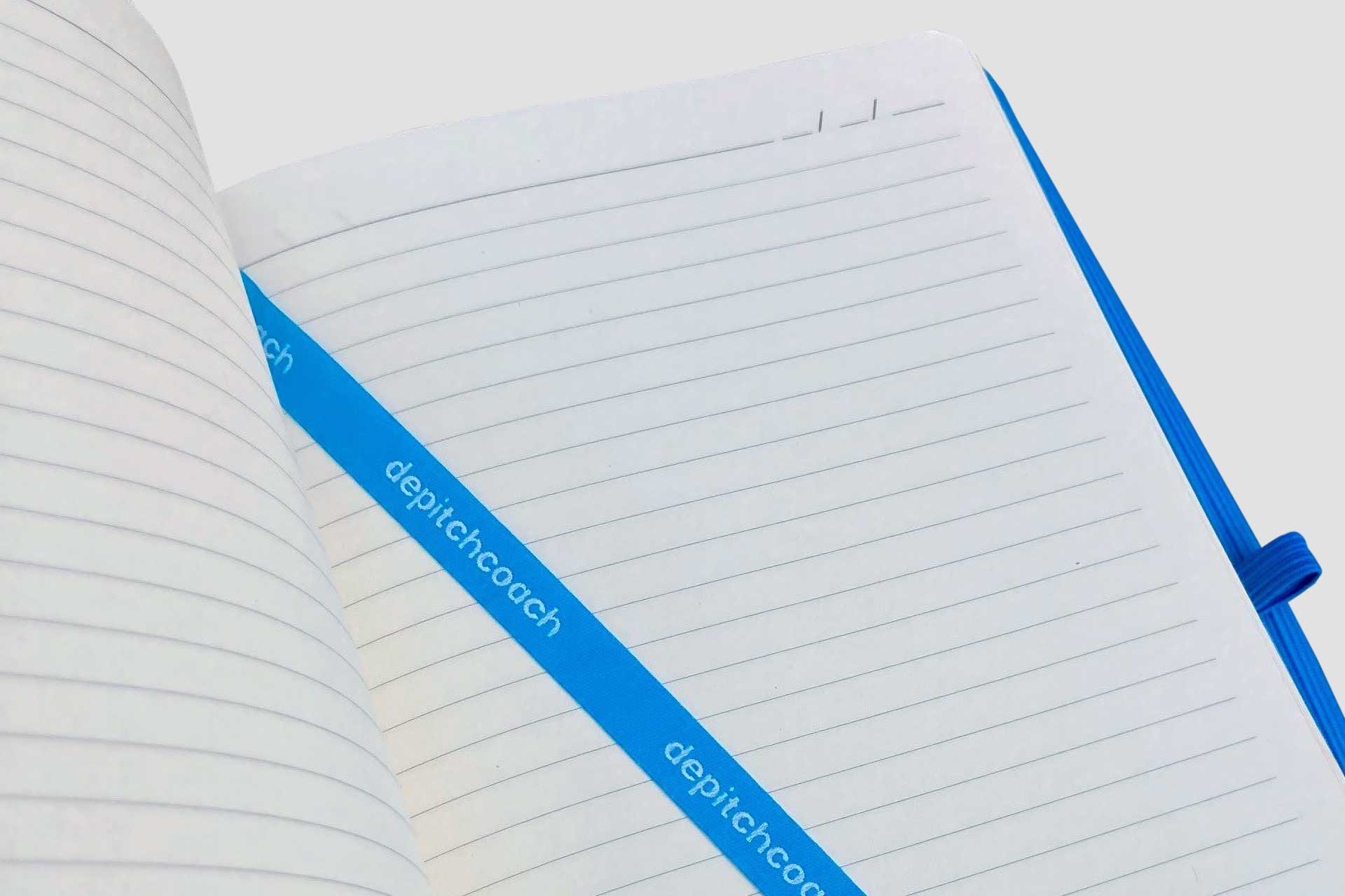 Opengeslagen notitieboek met blauw leeslint met logo ingeweven