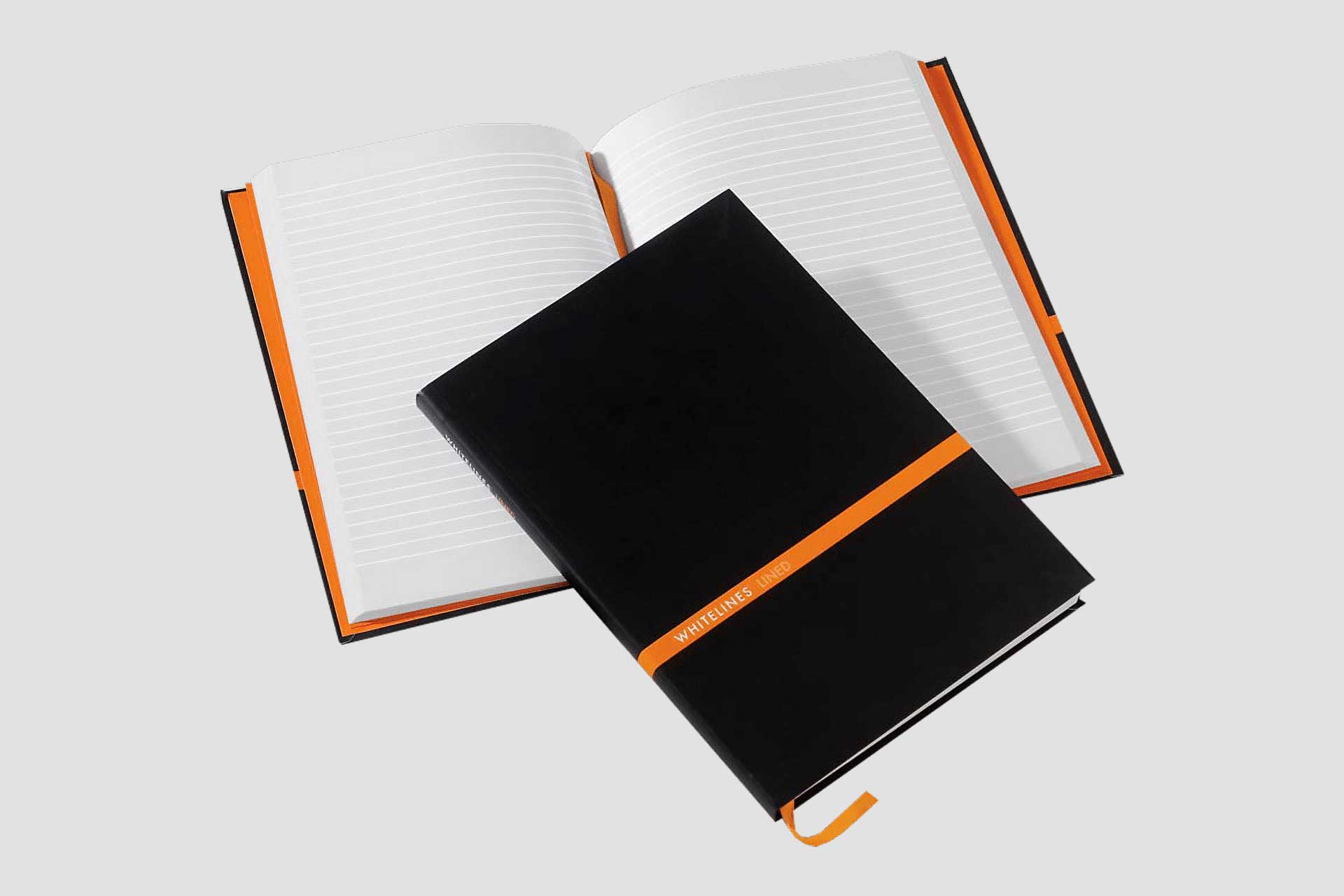 Opengeslagen notitieboek met papier met lijnen, daar op ligt een dicht notitieboek